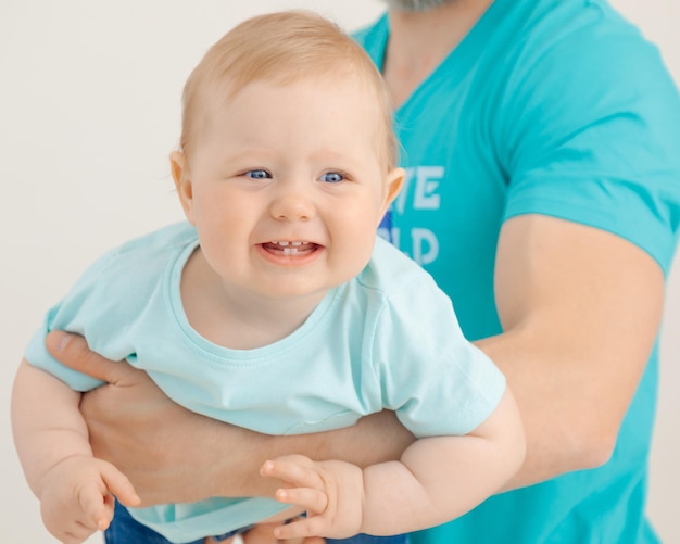 Retrato de homem atlético com braços bombeados segurando e levantando um bebê sorridente closeup branco b