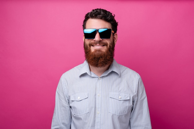 Retrato de homem barbudo alegre em casual, usando óculos escuros