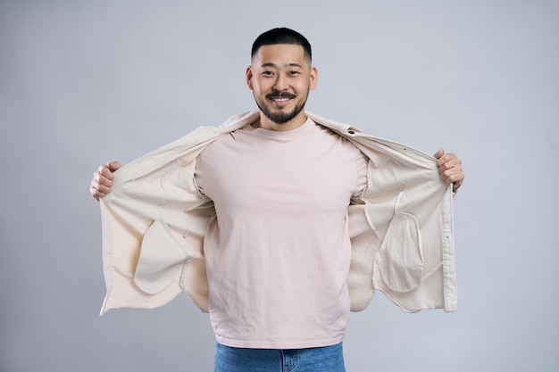 Retrato de homem barbudo asiático bonito abrindo camisa casual olhando para a câmera