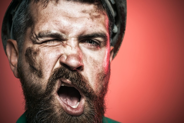 Retrato de homem barbudo com capacete de proteção, usando conceito de construção de negócios, construtor sorridente em disco