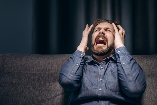 Retrato de homem barbudo gritando desesperadamente no escuro