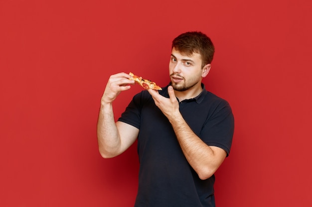 Retrato de homem bonito com barba com um pedaço de pizza nas mãos