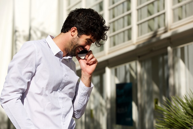 Retrato de homem bonito do lado de fora falando no telefone inteligente