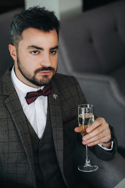 Retrato de homem bonito em um terno de negócio contém vidro. uma taça de champanhe na mão de um homem brutal