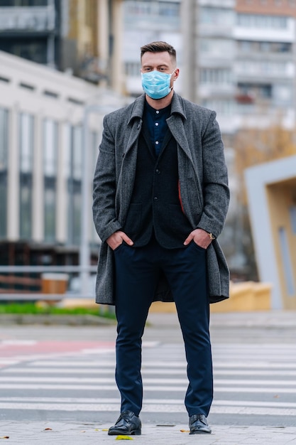 Retrato de homem bonito, usando uma máscara protetora, andando na cidade. Homem usando máscara para evitar germes, gases tóxicos e poeira. Prevenção da pandemia do vírus Corona de infecção bacteriana.