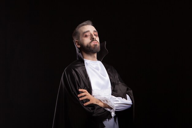 Retrato de homem bonito vestido com uma fantasia de Drácula para o Halloween. Dentes de vampiro. Demônio assustador.