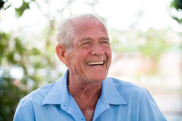 retrato de homem brasileiro sênior olhando para um ponto no pôr do sol e sorrindo. Forma horizontal, copie o espaço.