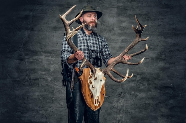 Retrato de homem caçador detém o crânio de um veado.