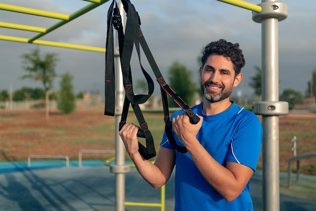 Retrato de homem caucasiano confiante durante treino com suspensão TRX na rua