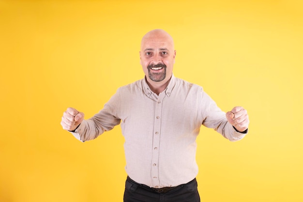 Retrato de homem caucasiano, gesto vencedor, homem bonito, vestindo casual sobre fundo amarelo