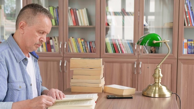 Retrato de homem caucasiano sênior trabalhando com livro na biblioteca pública Estudante adulto na biblioteca