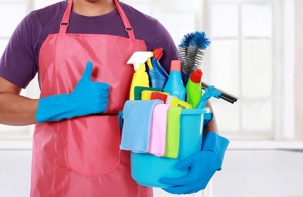 Retrato de homem com equipamentos de limpeza, polegares para cima