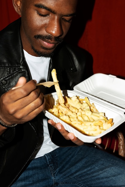 Foto retrato de homem comendo um delicioso prato de poutine