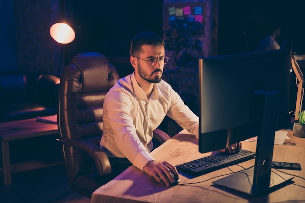 Retrato de homem concentrado sentado, trabalhando na mesa no computador