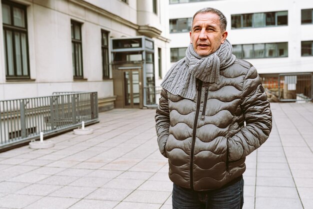 Retrato de homem de meia idade contra um fundo desfocado de fachadas de casas