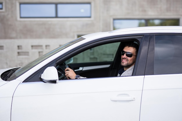 Retrato de homem de negócios bonito sentado em um carro branco