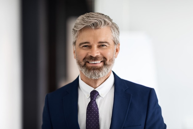 Retrato de homem de negócios de meia idade bonito sorridente vestindo terno olhando para a câmera