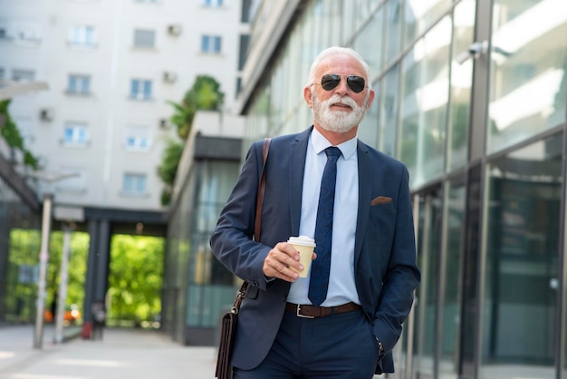 Retrato de homem de negócios sênior caminhando ao ar livre