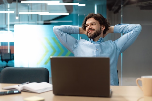 Retrato de homem de negócios sorridente relaxando na cadeira no escritório