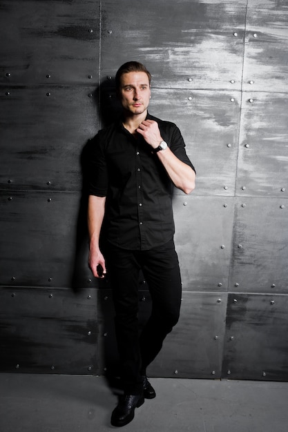 retrato de homem elegante vestir camisa preta contra a parede de aço.