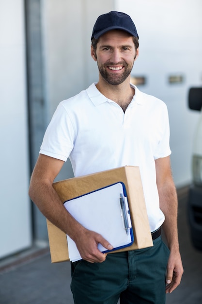 Foto retrato de homem entrega está segurando a caixa de papelão e posando