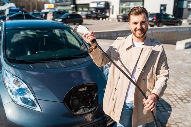 Retrato de homem estiloso com conector de carregamento de carro elétrico