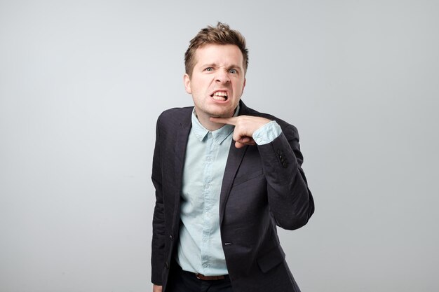 Retrato de homem europeu elegante com expressão entediada, mostrando sinal de matar cansado para explicar novo material