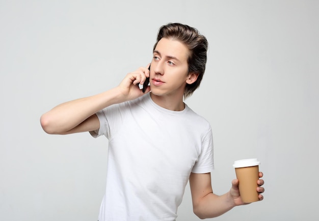 Retrato de homem feliz falando no telefone e tomando café