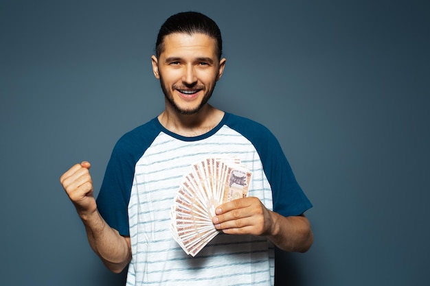 Retrato de homem feliz segurando notas de dinheiro da Moldávia no gesto azul sim