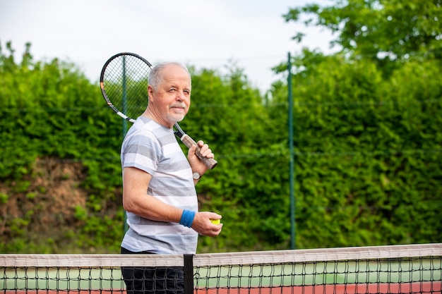 Retrato de homem feliz sênior antes de sua partida de tênis, conceito de esporte