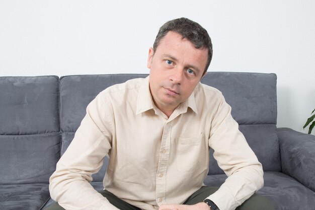 Retrato de homem feliz sentado no sofá em casa