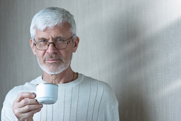 Retrato de homem grisalho, segurando uma xícara de café