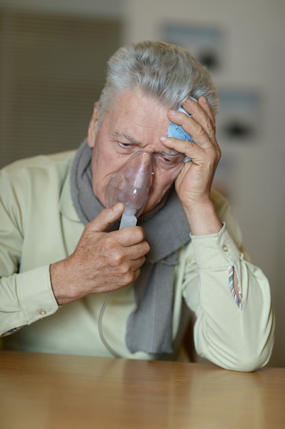 Retrato de homem idoso com inalação de gripe