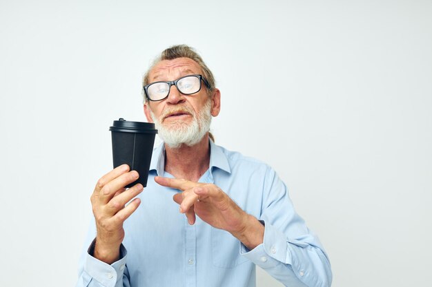 Retrato de homem idoso com um copo preto nas mãos um fundo isolado de bebida