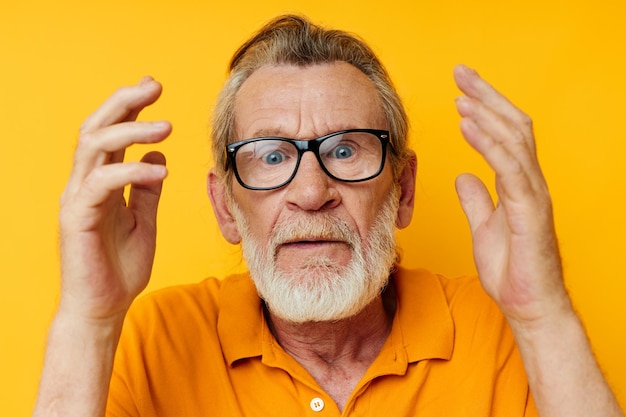 Retrato de homem idoso posando óculos de camiseta amarela fundo amarelo