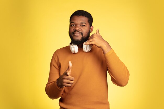 Retrato de homem jovem afro-americano isolado no fundo amarelo do estúdio.