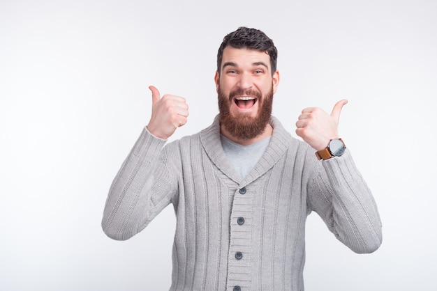 Retrato de homem jovem bonito espantado, mostrando os polegares