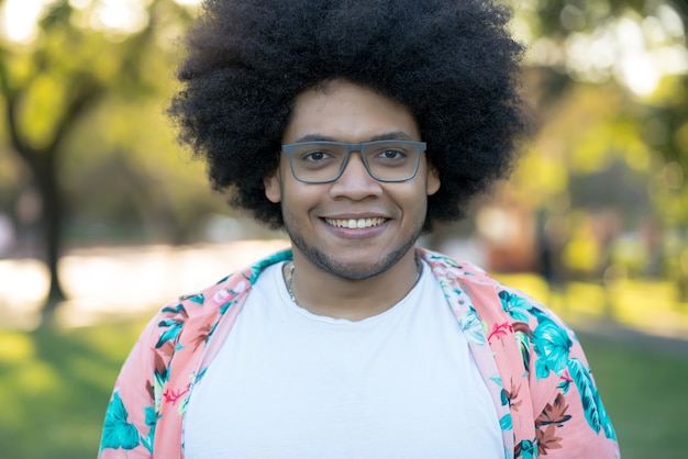 Retrato de homem latino afro confiante sorrindo em pé ao ar livre na rua. conceito urbano.