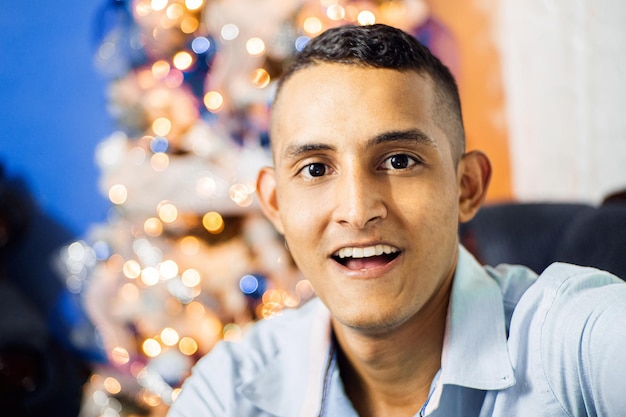 Retrato de homem latino-americano atrás de uma árvore de Natal