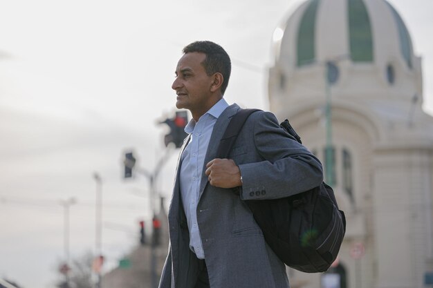 Retrato de homem latino de terno e mochila atravessando o pedestre