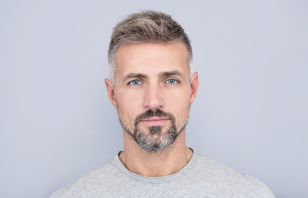 Retrato de homem maduro. cara adulto tem cabelos grisalhos. homem bonito com barba grisalha. moda de cabelo masculino. barbearia. cara de cara com a barba por fazer. cabelos e cuidados com a pele. skincare masculino. beleza dos homens.