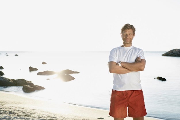 Retrato de homem maduro confiante com fones de ouvido e smartwatch na praia