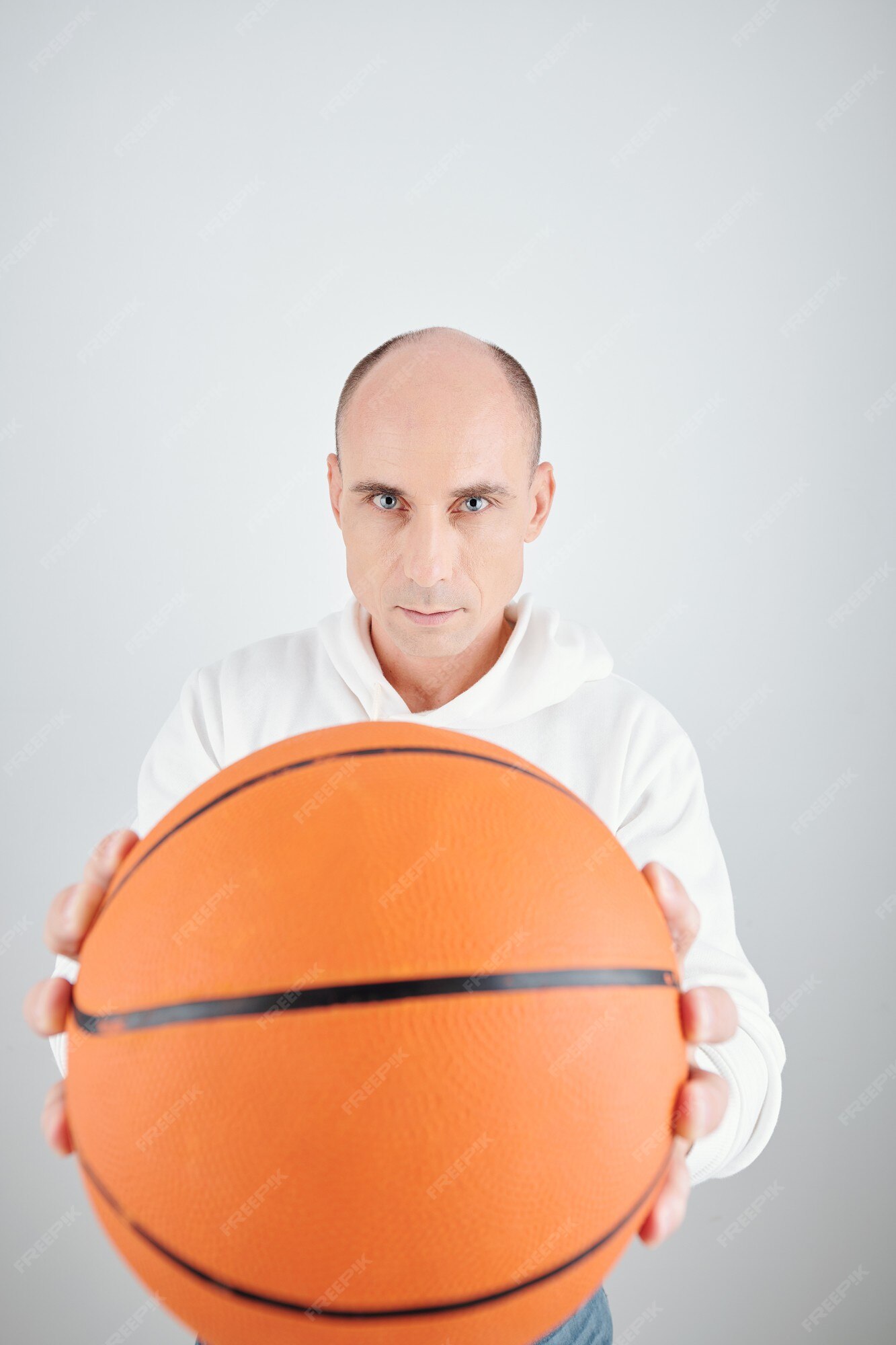 Homem careca de meia-idade segurando uma bola de basquete sobre