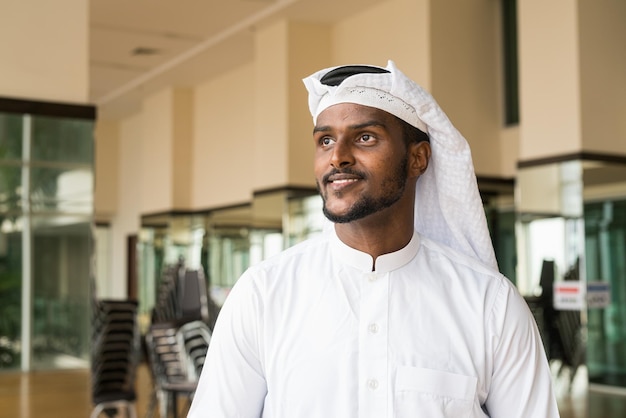 Retrato de homem muçulmano africano vestindo roupas religiosas um cachecol no escritório enquanto pensava