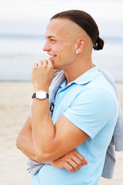 Retrato de homem na praia posando de camiseta azul