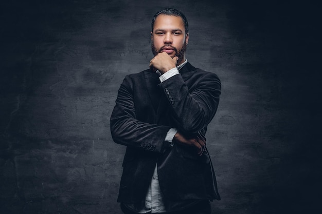 Retrato de homem negro barbudo com braços cruzados, vestindo um terno de lã.