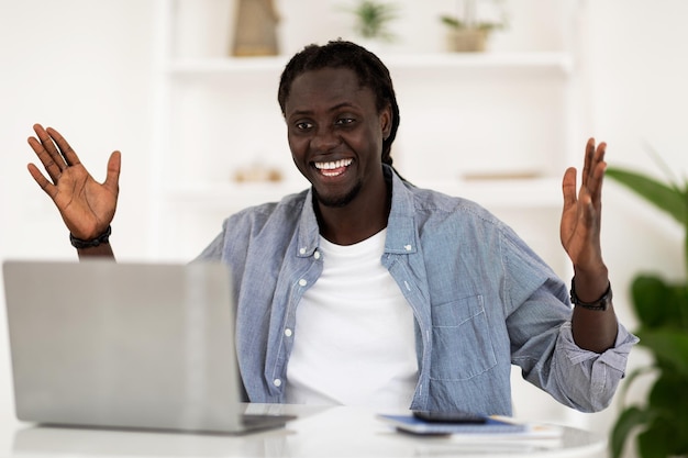 Retrato de homem negro feliz olhando para laptop e exclamando com emoção