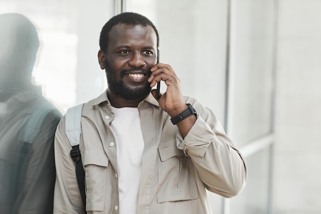 Retrato de homem negro sorridente falando por smartphone ao ar livre, copie o espaço