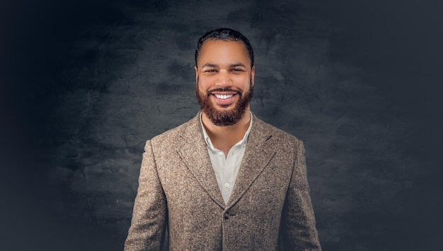 Retrato de homem negro sorridente sobre fundo cinza escuro.