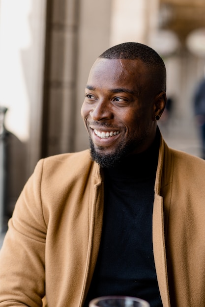 Retrato de homem negro sorrindo, olhando para longe.